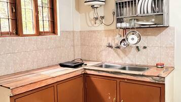 A kitchen with a sink, cabinets, a stove, and a dish rack.