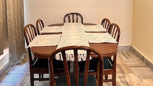 Zona de menjador amb una taula de fusta, sis caires i un penjall.