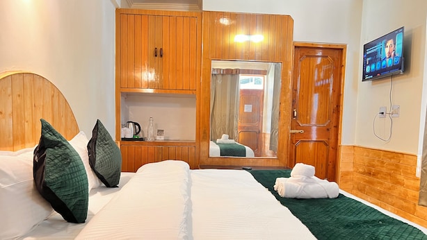 Habitació d'hotel amb llit, armari, mirall i televisió.