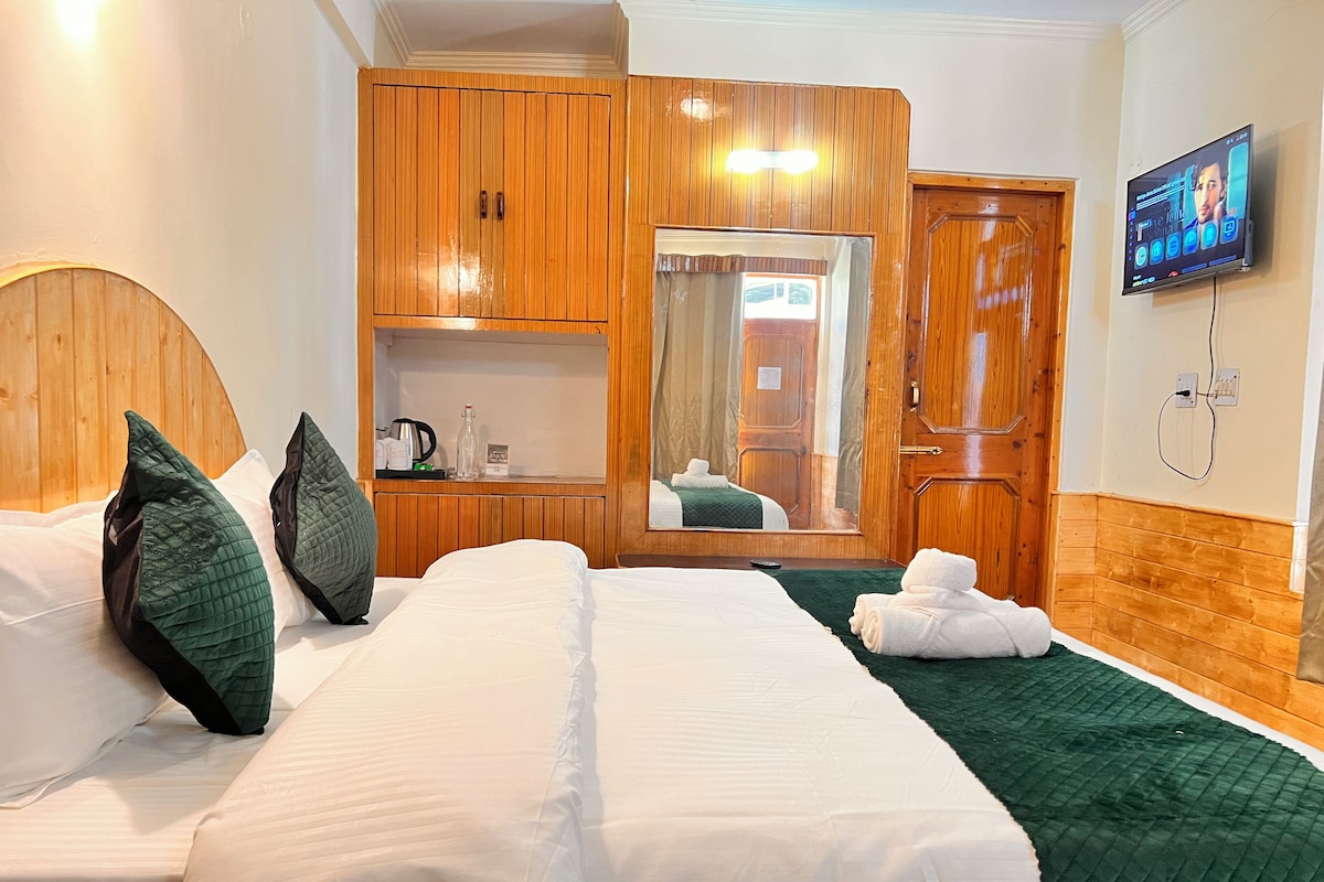 Quarto de hotel com cama, guarda-roupa, espelho e televisão.