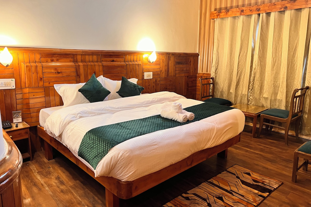 Quarto com painéis de madeira, uma cama, duas luminárias de cabeceira, uma cadeira e uma mesa pequena.