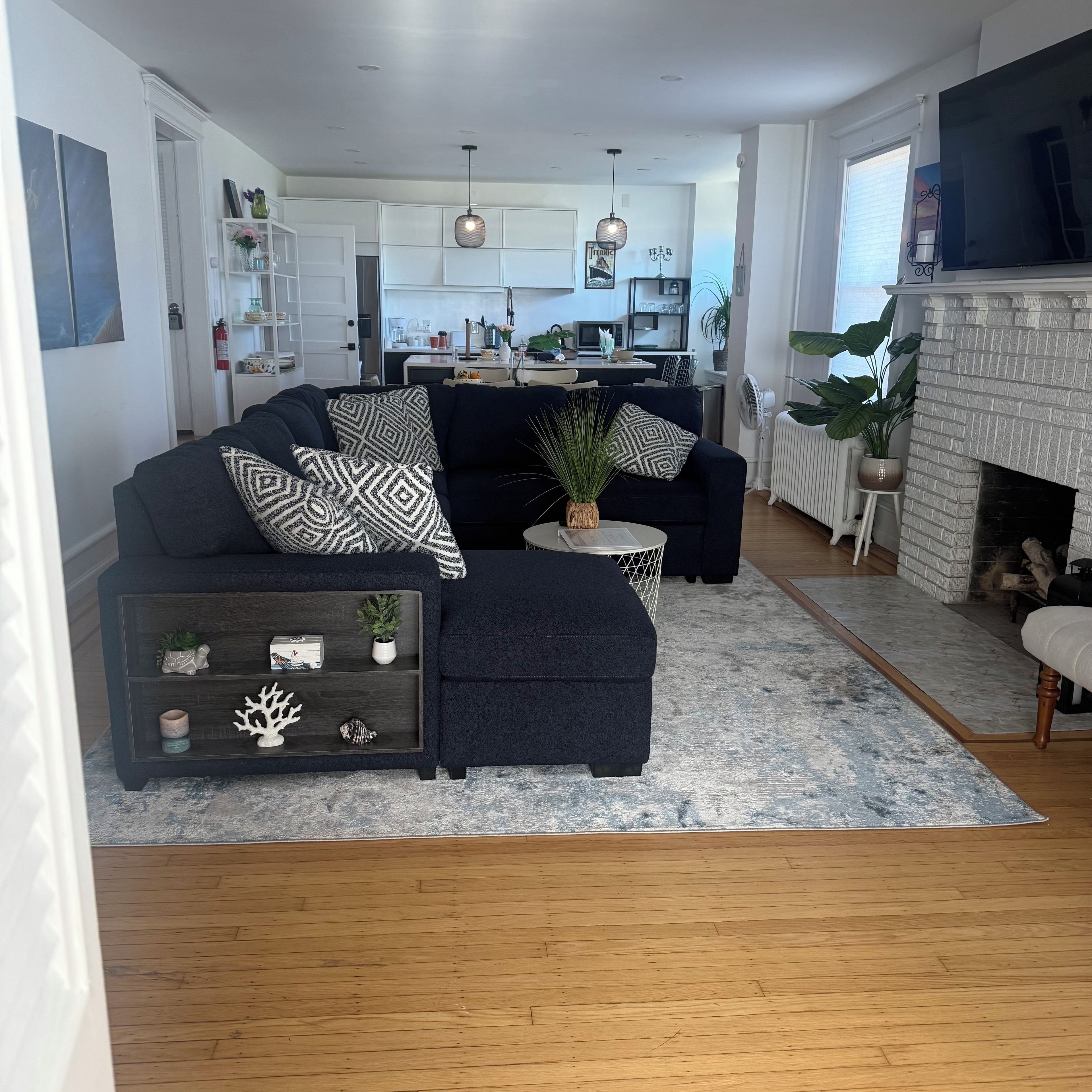 Een moderne woonkamer met een donkerblauwe bank, een klein bijzettafeltje en een open haard.