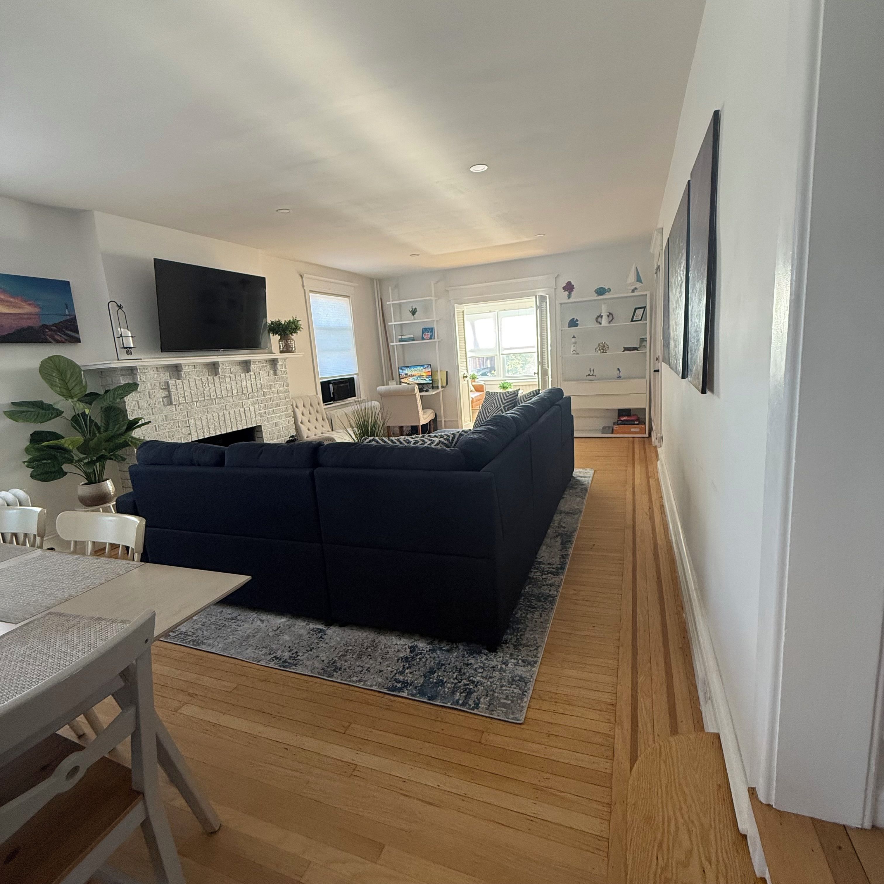 A modern living room with a dark blue sofa, a flat-screen TV, and a fireplace.