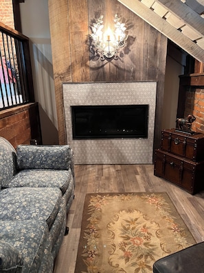 A living room with a fireplace, a sofa, a rug, and a wall-mounted TV.