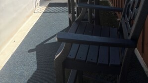 A balcony with a table and chairs, a view of the street, and a wooden fence. - Adorable Old World Livery Stable with balcony overlooking Downtown Madison (Madison)