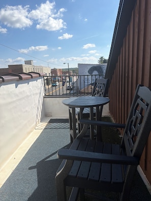 A balcony with a table and chairs, a view of the street, and a wooden fence. - Adorable Old World Livery Stable with balcony overlooking Downtown Madison (Madison)