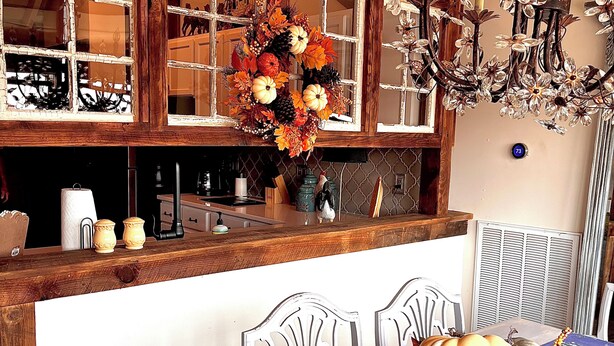 A dining area with a table set for two, a chandelier, and a kitchen in the background. - Adorable Old World Livery Stable with balcony overlooking Downtown Madison (Madison)
