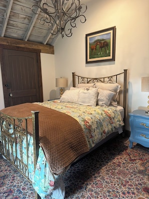 A bedroom with a bed, a chandelier, a door, and a painting on the wall. - Adorable Old World Livery Stable with balcony overlooking Downtown Madison (Madison)