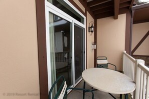 Eine Terrasse mit Tisch und Stühlen, einer Glastür und einer Laterne.