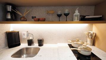 Una cocina con un lavamanos de acero inoxidable, una cafetera, una cocedora de arroz y una estufa.