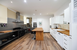 Una cocina moderna con una isla central, electrodomésticos de acero inoxidable y suelo de madera.