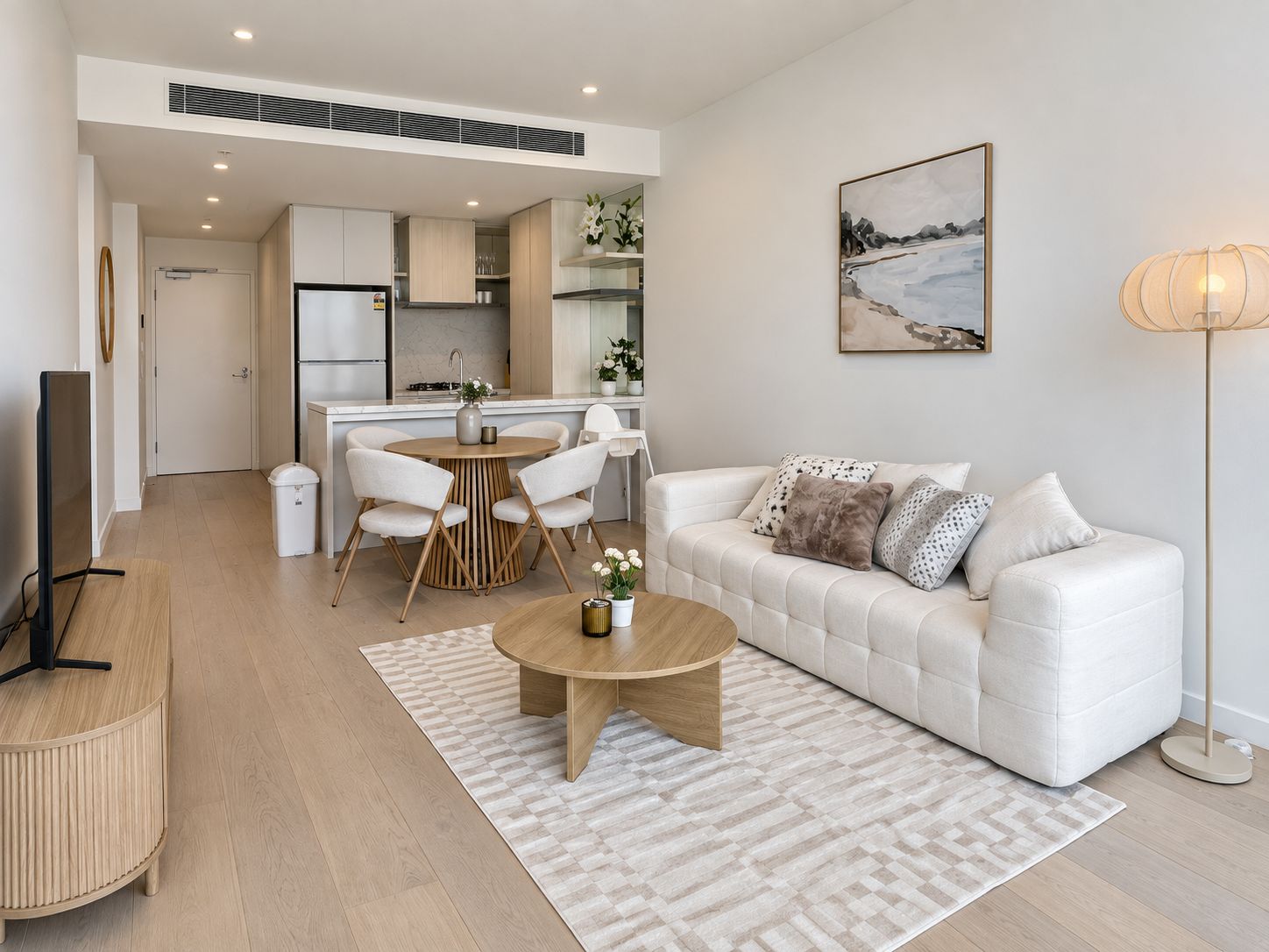 A modern living room with a sofa, coffee table, and a dining area with chairs and a table.