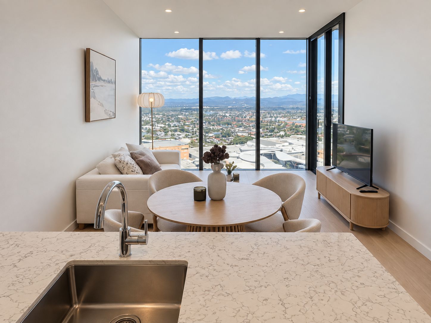 A modern living room with a large window, a sofa, a coffee table, and a TV.
