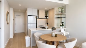 Een moderne keuken met een centraal eiland, witte kasten en een eetgedeelte met een ronde tafel en vier stoelen.