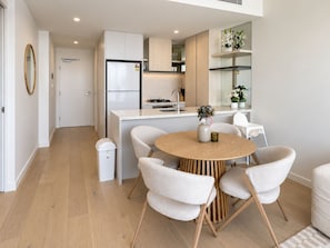 Una cocina moderna con una isla central, armarios blancos y un comedor con una mesa redonda y cuatro sillas.