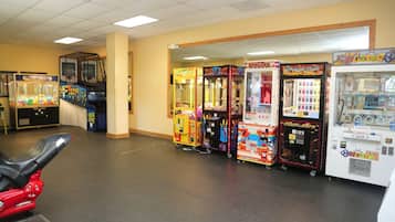 A room with arcade games, a motorcycle, and a vending machine.
