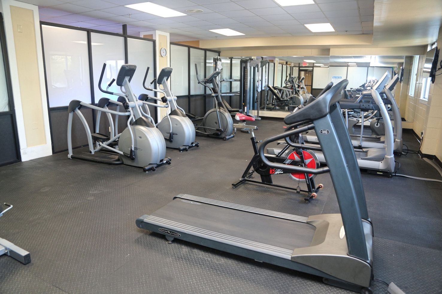 Une salle de sport équipée de tapis de course, de vélos elliptiques et de matériel de musculation.