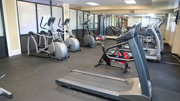 Une salle de sport équipée de tapis de course, de vélos elliptiques et de matériel de musculation.