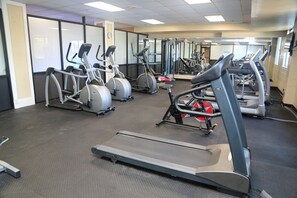 Une salle de sport équipée de tapis de course, de vélos elliptiques et de matériel de musculation.