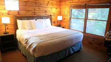 Une chambre à coucher de style cabane en bois, avec un lit, deux lampes de chevet, une fenêtre et un téléphone.