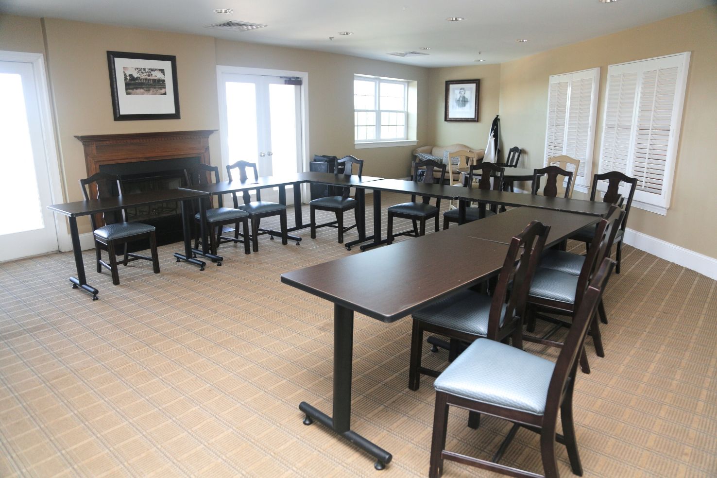 A conference room with a long table, chairs, a fireplace, and framed pictures on the walls.