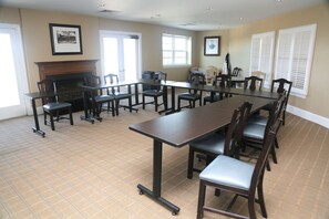A conference room with a long table, chairs, a fireplace, and framed pictures on the walls.