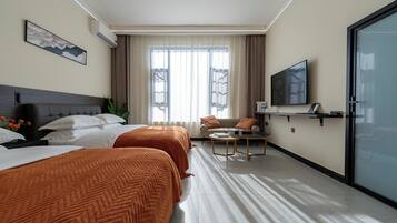 A hotel room with two beds, a sofa, a TV, and a desk.