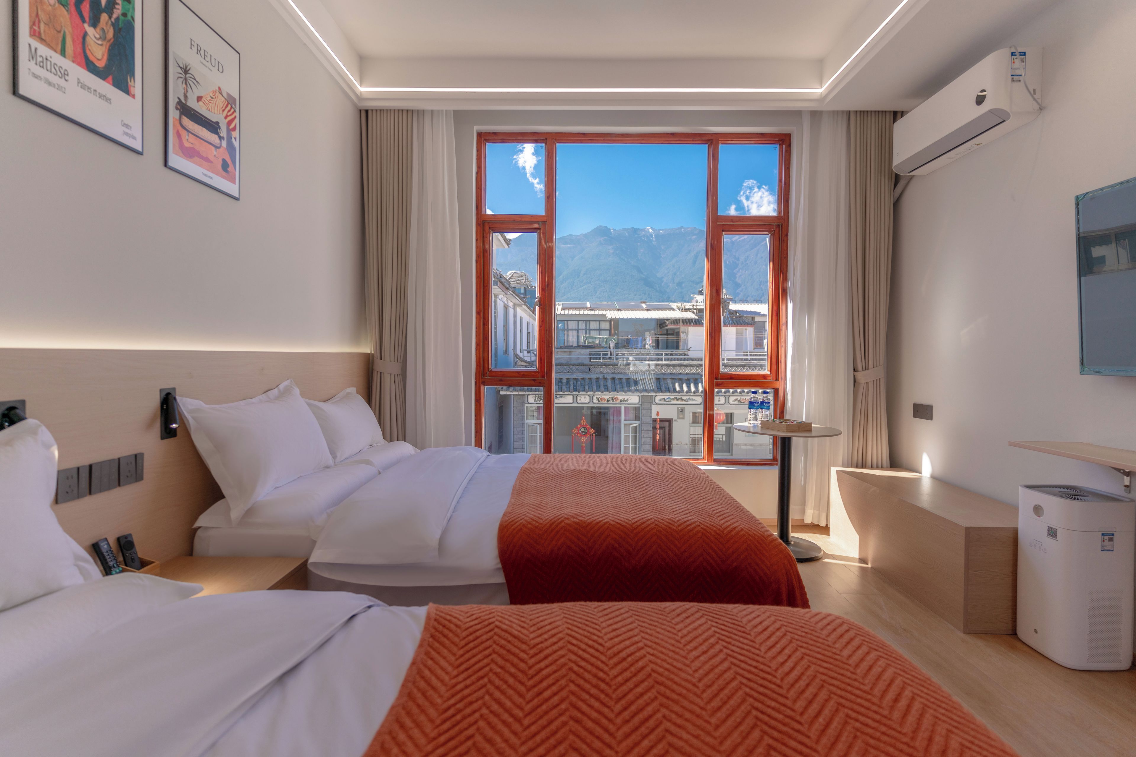 Una habitación de hotel con un ventanal grande, una cama, un escritorio y una silla.