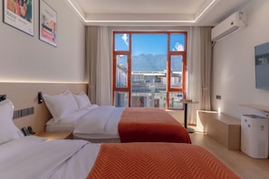Habitació d'hotel amb una finestra gran, un llit, una taula de treball i una cadira.