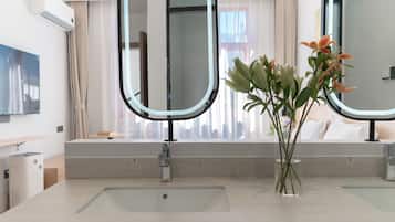 Un baño moderno con un espejo grande, un lavabo y un florero con flores.