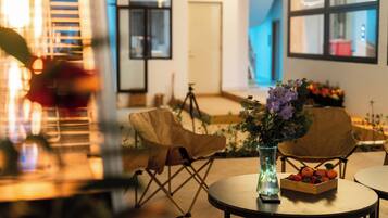 A room with a table, chairs, a vase with flowers, and a fruit basket.