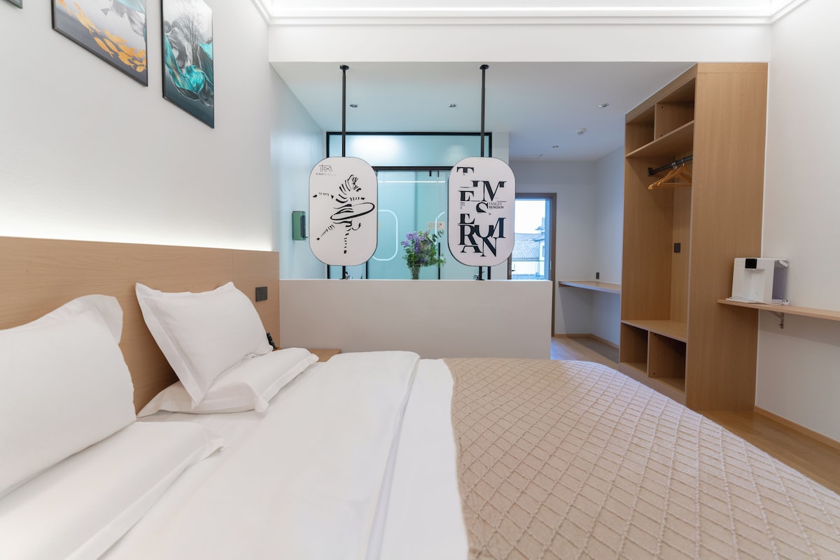 Habitació d'hotel moderna amb un llit gran, un armari i un mirall amb detalls decoratius.