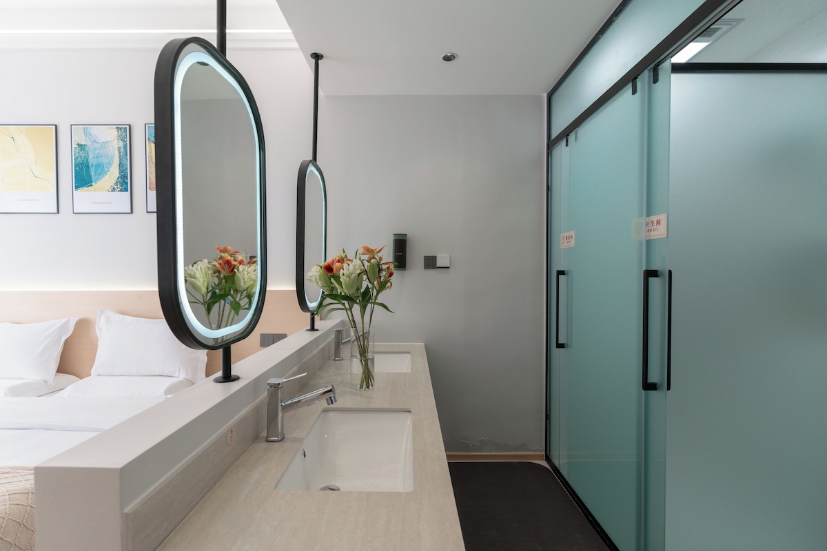 Un bany modern amb un mirall gran, un lavabo i un vàter. Hi ha dues obres d'art amb marc a la paret.