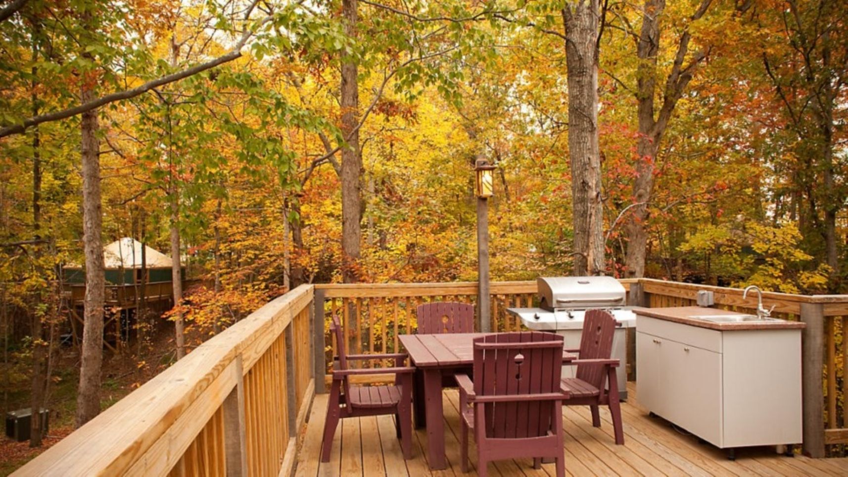 Une terrasse dotée d’un barbecue et d’un évier, entourée du feuillage automnal.