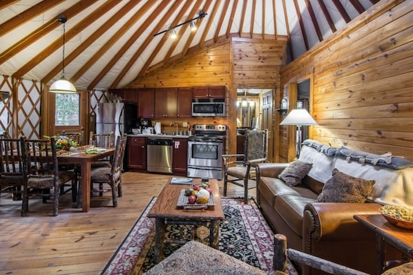 A cozy interior with a wooden dining table, a sofa, and a kitchen area with modern appliances.