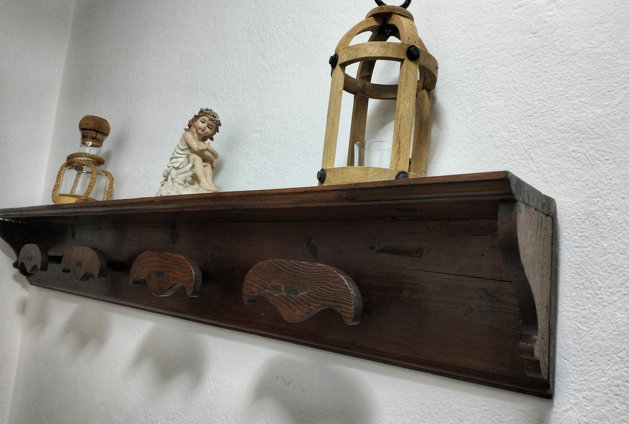 Ein Holzregal mit verschiedenen Gegenständen, darunter eine Figur, eine Laterne und eine Flasche.