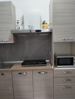 A kitchen with a microwave, a toaster, and a kettle on the countertop.
