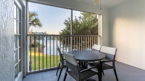 A balcony with a table and chairs, a view of a lake, and a railing. - Orlando | Orlando Resort Stay | Pool & Water Park | 2BR (Orlando)