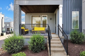 A modern building with a covered porch, outdoor seating, and a staircase leading to the entrance. - Nashville Overlook (Nashville)