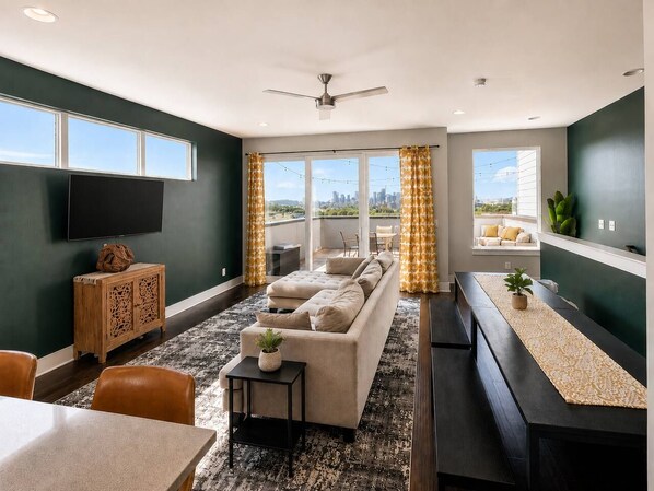 A modern living room with a sofa, a TV, and a dining area with a table and chairs. - Nashville Overlook (Nashville)