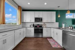 A modern kitchen with white cabinets, stainless steel appliances, and a view through the window. - Nashville Overlook (Nashville)
