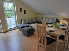 A dining area with a table set for four, a sofa, and a window with a view of greenery.