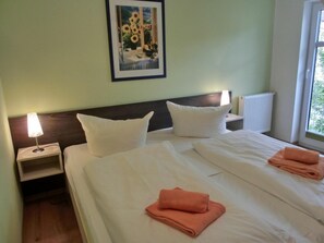 Ein Hotelzimmer mit einem Bett, zwei Kissen, einem Nachttisch mit Lampe und einem gerahmten Bild an der Wand.