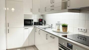 Eine moderne Küche mit weißen Schränken, einer Mikrowelle, einer Kaffeemaschine und einem Blumentopf auf der Arbeitsfläche.