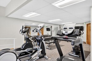 Ein Fitnessstudio mit verschiedenen Trainingsgeräten, darunter Laufbänder, Ergometer und Kraftgeräte.