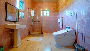 Et badeværelse med vask, toilet, brusebad og et spejl.