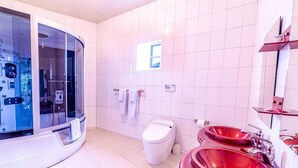 Et moderne badeværelse med et brusebadekar i glas, et hvidt toilet og røde håndvaske.