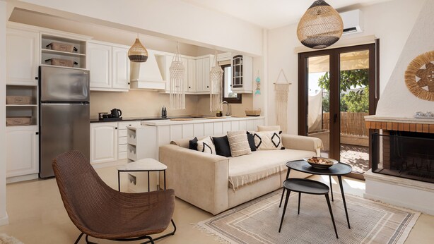 Una cocina moderna con armarios blancos, un refrigerador de acero inoxidable y un comedor con una mesa redonda y sillas.