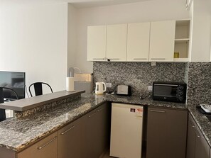 Eine kleine Küche mit Mikrowelle, Toaster und Kaffeemaschine auf der Arbeitsfläche.