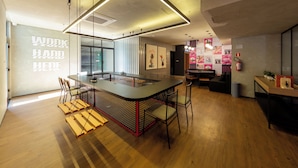 Um interior moderno com uma ilha central, banquetas de bar e diversos assentos, incluindo um sofá e cadeiras.
